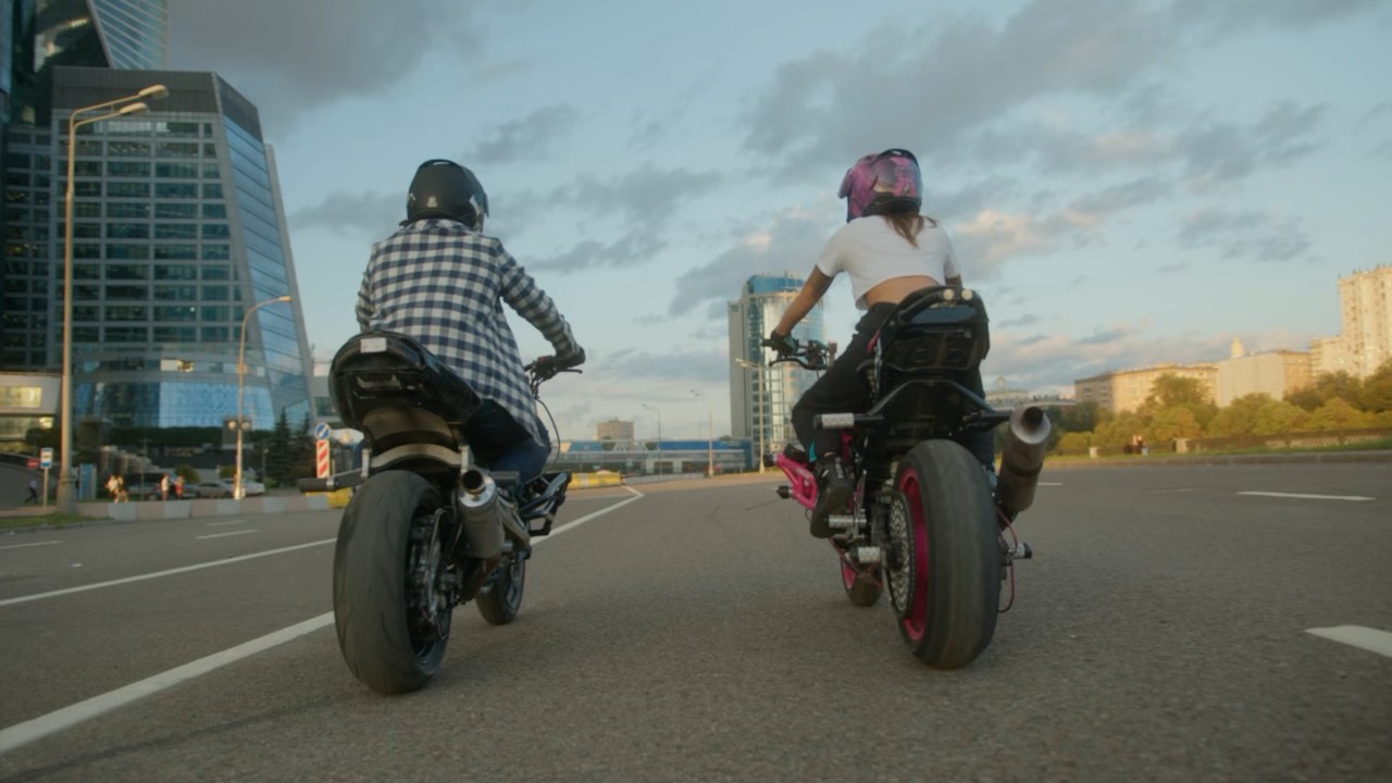 Two riders on a road at dusk.